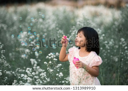 Asia Cute girl plays soap bubbles in a flower garden.