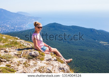 girl sitting on the edge of a mountain and smiling
