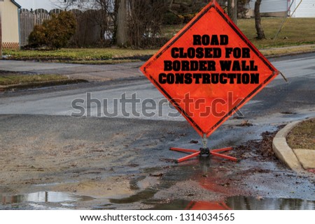 Orange diamond shaped Road Closed for border wall construction sign blocking a residential street