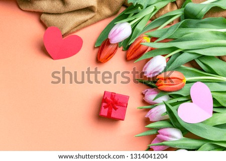 Red gift box and tulips over table with place for text. Concept of declaration in love or give a gift