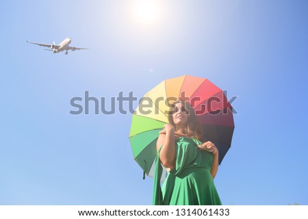 The plane against the blue sky and a woman with an umbrella. The sun shines
