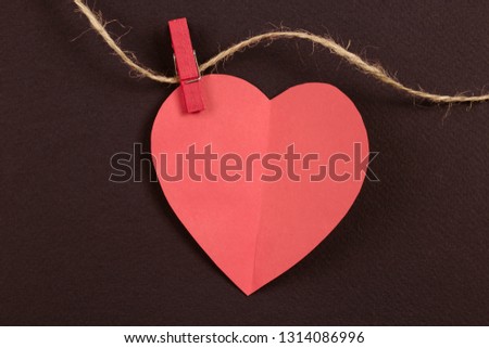 Paper heart of coral color on a thread with red clothespin on a red background. Banner for you design.