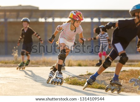 Young girl training inline skating with other children on rollerdrome