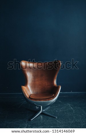 Modern stylish leather brown armchair, dark blue background Royalty-Free Stock Photo #1314146069