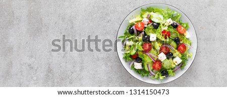 Vegetable salad with fresh cucumber, tomato, olive, onion, lettuce and feta cheese. Healthy food. Top view. Banner Royalty-Free Stock Photo #1314150473