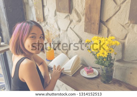 Side view of cute Asian girl reading book