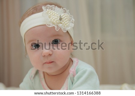 Portrait of a newborn girl with headwear. Cute little girl 5 months old. Happy baby in the room