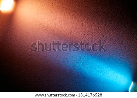 Blue and cream ray of light shine on a textural background to meet each other