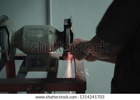 Worker sharpen the knife blade using grinding wheel in the workshop at a factory reveal orange spark with flame