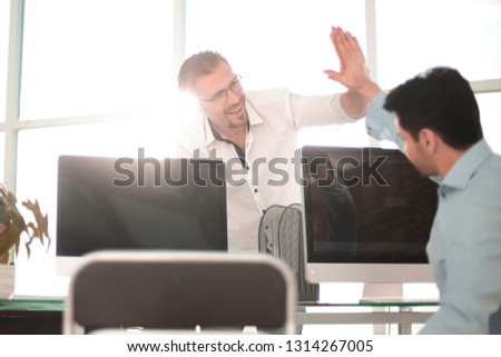employees give each other a high five over the computer Desk