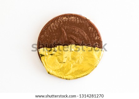 Gold foiled wrapped chocolate coins on a white background Royalty-Free Stock Photo #1314281270