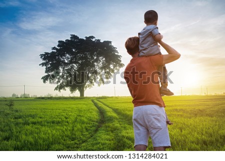 Father and son playing in the park at the sunset time