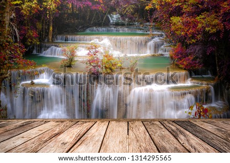 Huai Mae Khamin Waterfall during the rainy season with leaves changing color and old brown wood chalets in Thailand