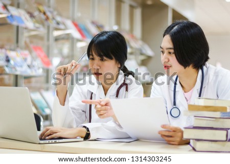 Two young women doctor discussing case in bright office 