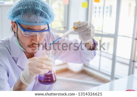 A male scientist testing his experiment in a science lab where there are chemical substances and equipment. Bio technology concept. 