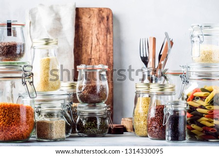 Stocks or set of cereals, pasta, groats, organic legumes and useful seeds in glass jars. Vegan source of protein and energy resources. Healthy vegetarian food. Domestic life scene. 