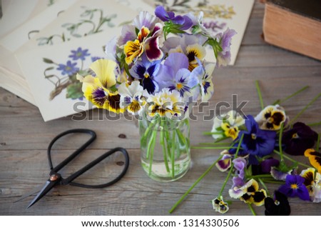 Bouquet of colorful pansies in a glass bottle on a gray wooden t