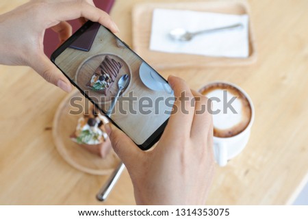 Point of view of a young woman taking a photo of her chocolate cake with her smartphone, Picture of cake on screen