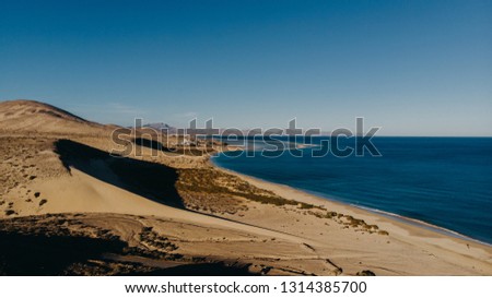 single dune in the beach half shadow half light aerial canarias fuerteventura
