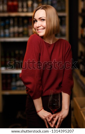 Picture of blonde woman with glass in hands at store with wine