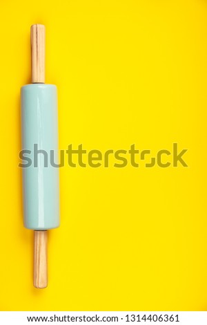Blue rolling pin on yellow background, flat lay