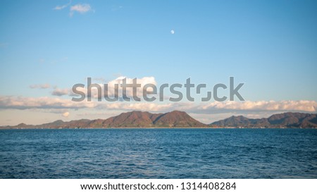 Beautiful nature scene seen on the island of Okunoshima, also known as the "Bunny Island", which is a small island located in the Inland Sea of Japan, with a waxing gibbous moon in the sky.