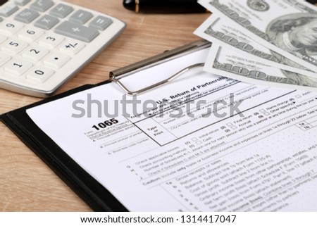 
1065 tax form lies near hundred dollar bills, calculator and  pen on a Table. US Return for parentship income Royalty-Free Stock Photo #1314417047