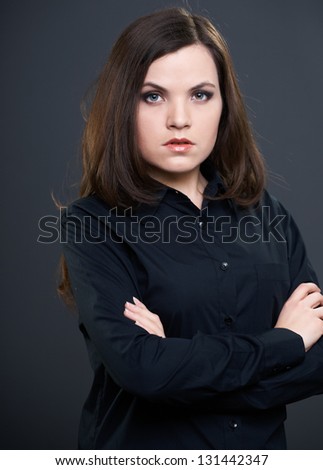 Attractive young woman in a black shirt with folded hands. On a gray background