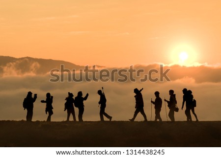 Silhouettes of hikers with backpacks enjoying sunset view from top of a mountain, Silhouette tourists and photographers with beautiful sunrise