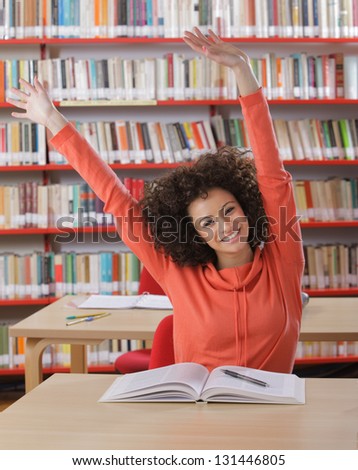 Happy female student with arms raised smiling