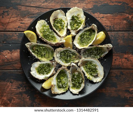 Grilled oysters with Parsley and garlic butter served with parmesan and lemon wedges