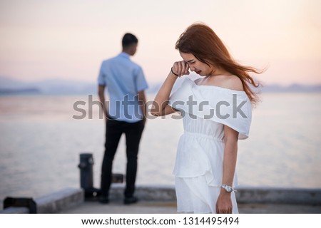 Young couple break up at the sea deck. Girl crying and walk away from man in concept love hurts,hard relationship,sad love story,when love is ended. Broken heart syndrome. How to fix a broken heart. Royalty-Free Stock Photo #1314495494