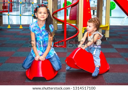 Little boy and girl on a playground. Happy kid in kindergarten or preschool. Children having fun mall. Toddler on a swing.