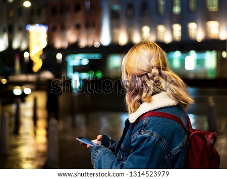 Young girl on the street with a mobile phone in his hands. View from the back. Royalty-Free Stock Photo #1314523979