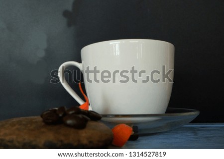 Hot black coffee and roasted coffee beans with flowers placed on the table, side view