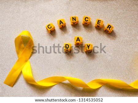 golden ribbon and words made up of children's plastic beeches. concept - a symbol of childhood cancer, pediatric oncology.