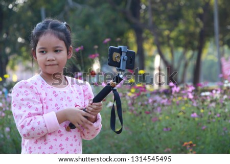 Little girl child taking photos by smartphone in outdoors garden - Image