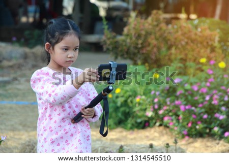 Little girl child taking photos by smartphone in outdoors garden - Image
