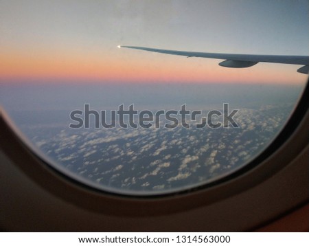 Sunrise and clouds sky and wing as seen through window of an aircraft.