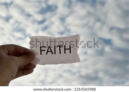 Woman holding white torn paper with word Faith over the sky background