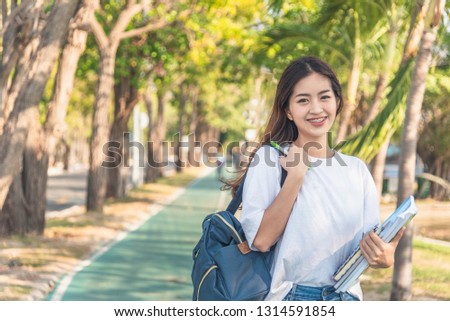 A female college student reading a book while lying on the park