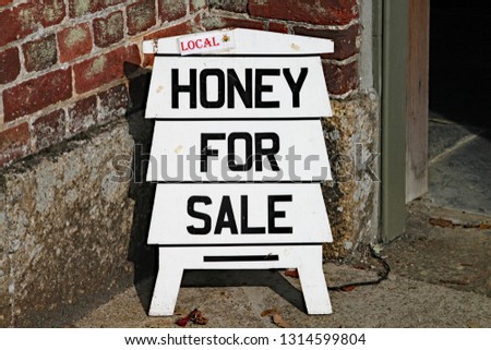 Sign in the shape of a beehive advertising honey for sale.