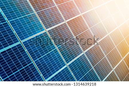Close-up surface of lit by sun blue shiny solar photo voltaic panels. System producing renewable clean energy. Renewable ecological green energy production concept.