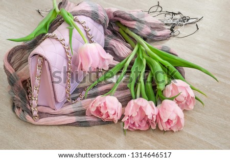 Pink tulips with bag and scarf on wooden background