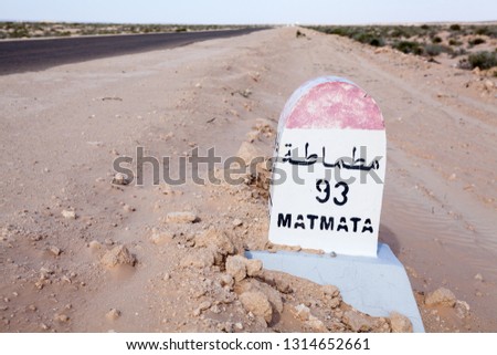 Milepost on a desert asphalt road to the Matmata destination, Tunisia, Africa. Road passing through the salt lake Chott El Djerid. Copyspace