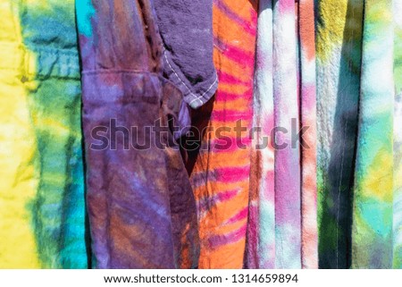 Brightly colored boho tie dyed garments hanging together - background - selective focus