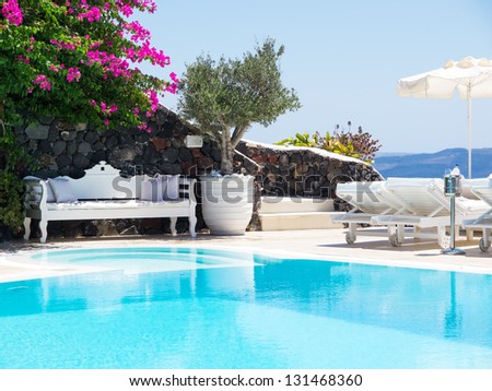 A luxury swimming pool situated in the town of oia on the greek island of santorini with a view of volcano in the distance. Royalty-Free Stock Photo #131468360