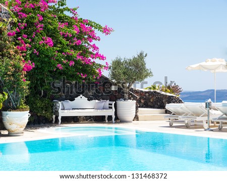 A luxury swimming pool situated in the town of oia on the greek island of santorini with a view of volcano in the distance. Royalty-Free Stock Photo #131468372