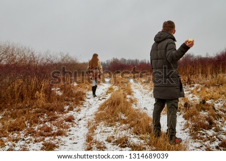 Couple in love on autumn or winter walk. Guy doesn't give an Apple to a girl. Quarrel and resentment