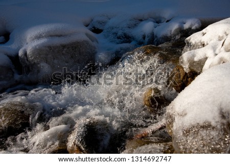Water spray from the waves . High shutter speed picture of river water flowing, in the winter. Texture river creek stream. Waterfal